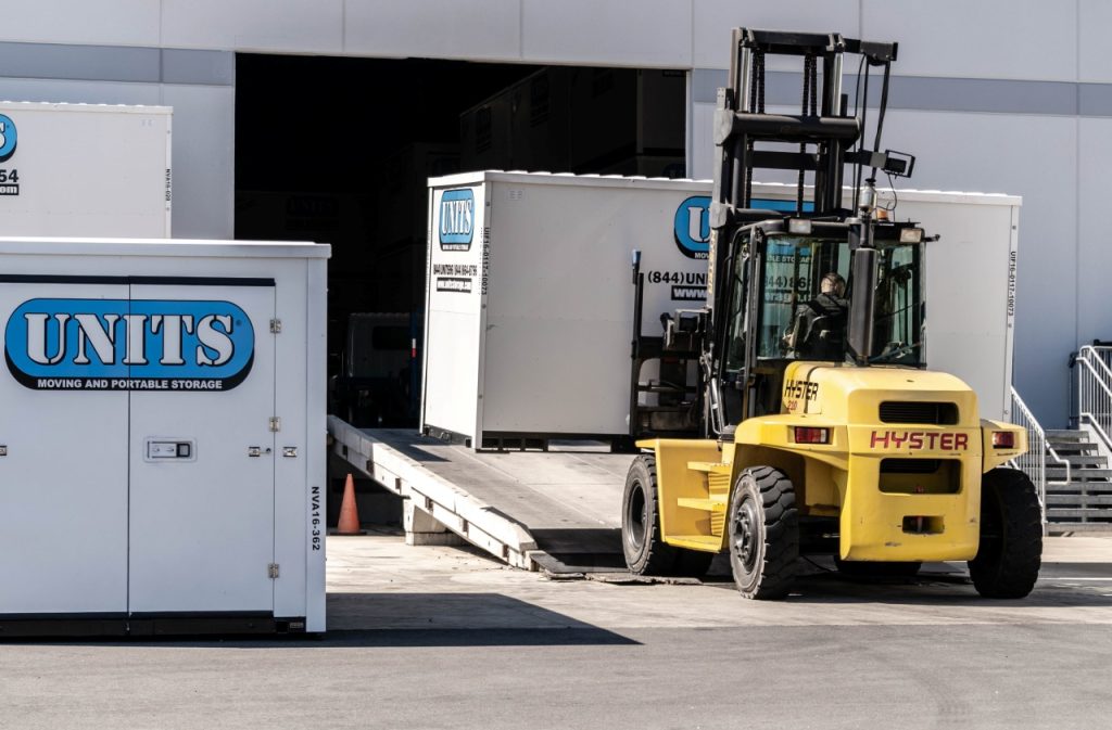 image of a forklift picking up a portable storage container